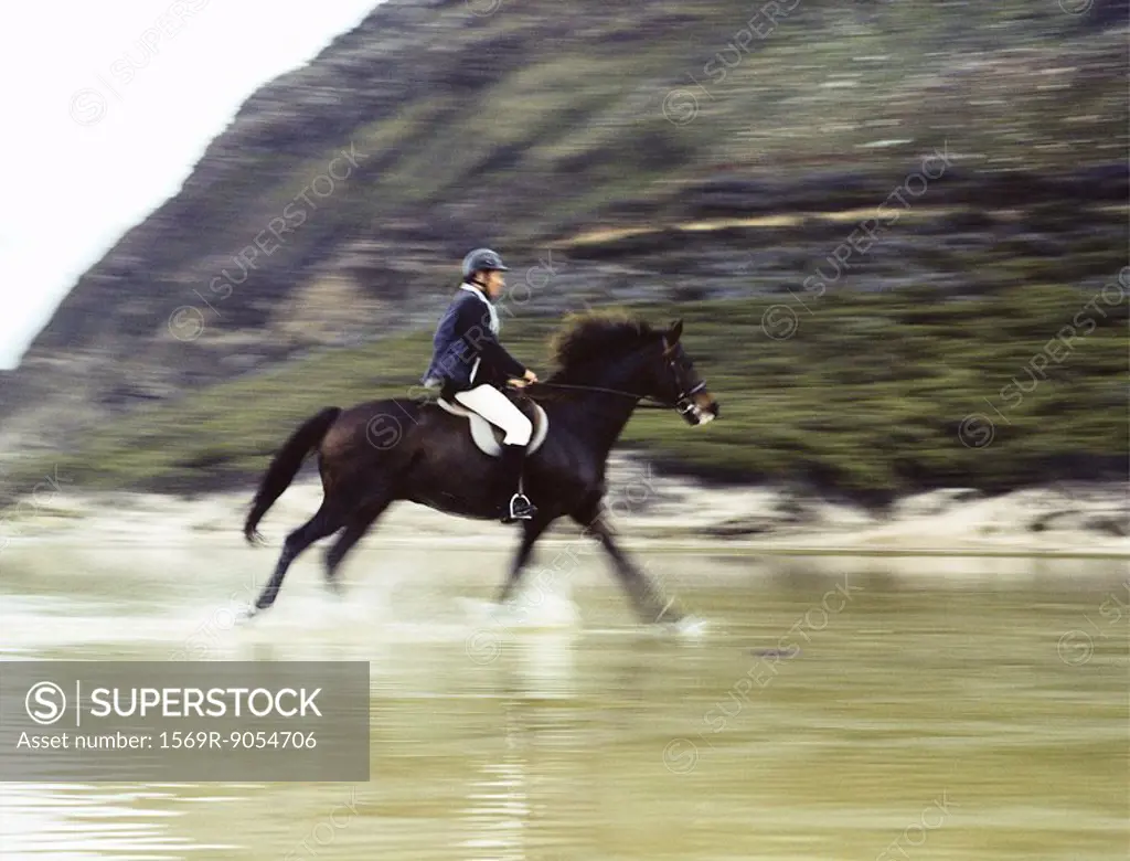 Man riding horse through water, blurred motion
