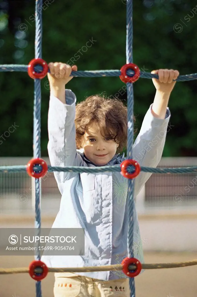 Little girl on rope climbing net, portrait