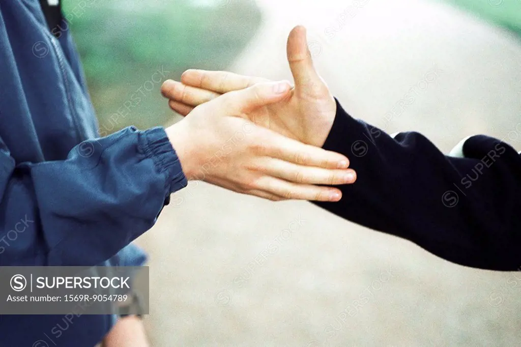 Boys reaching to shake hands, cropped view