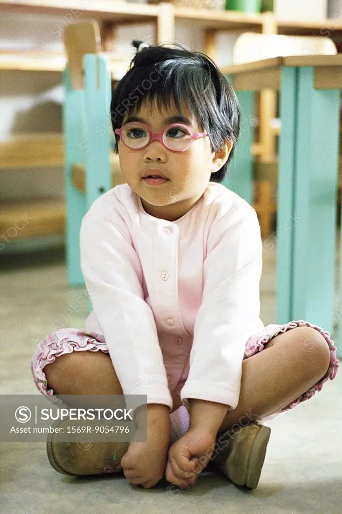 Little girl sitting indian style on floor