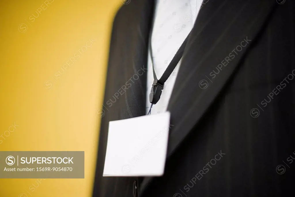 Man in suit wearing blank nametag around neck, cropped