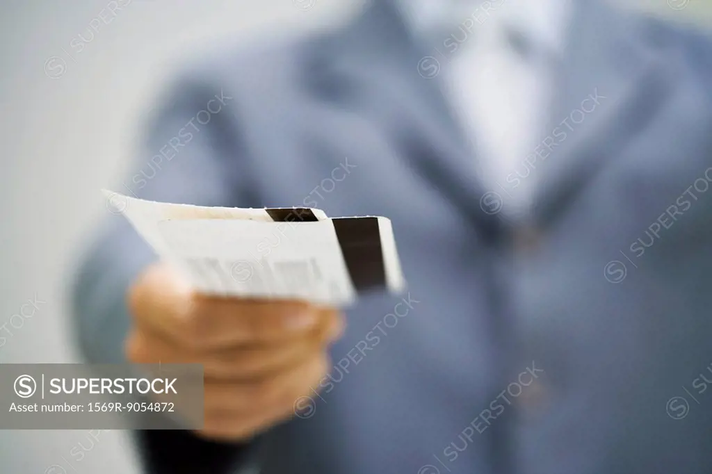 Man in suit holding out tickets