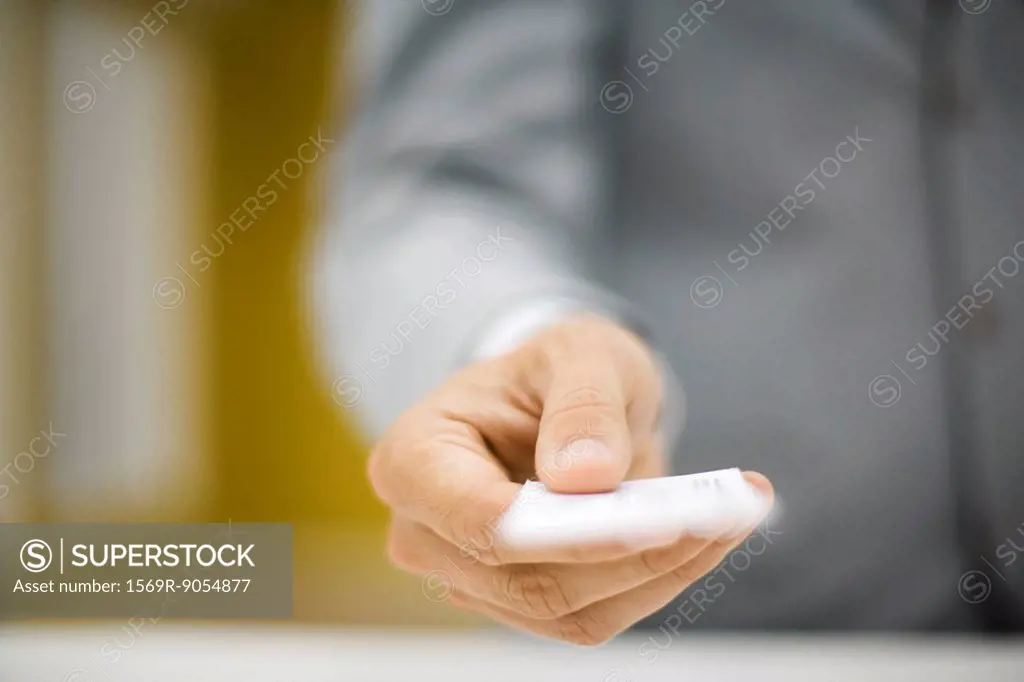 Man in suit holding out business card, cropped