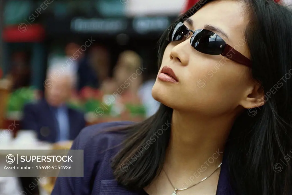 Woman wearing sunglasses, looking up