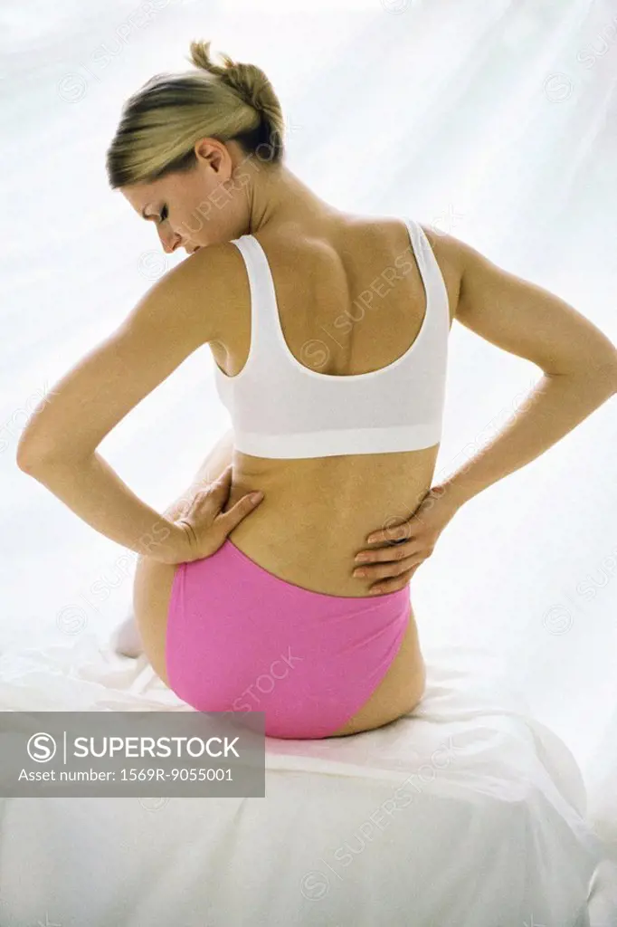 Woman in underwear, holding lower back
