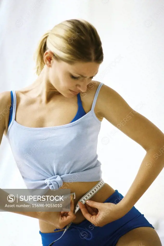 Woman in sports clothing, measuring waist