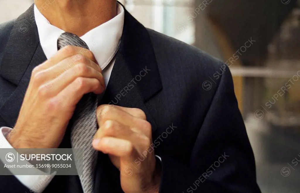 Man adjusting tie, cropped