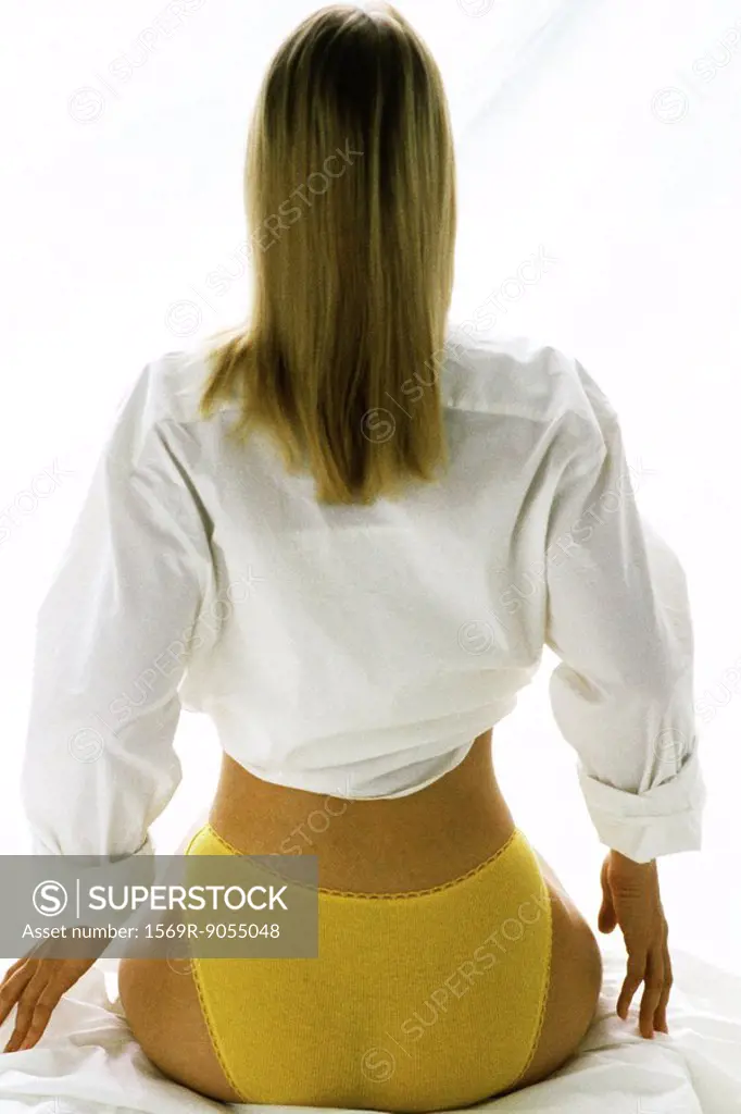 Woman wearing underwear and button down shirt, rear view