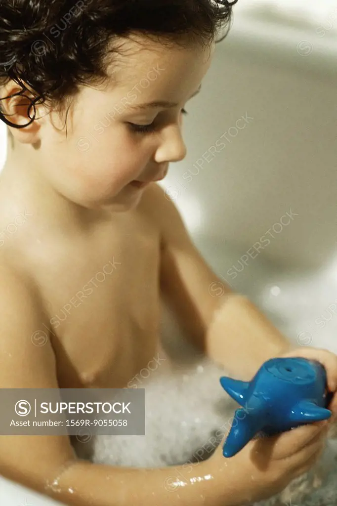 Little boy taking bubble bath with toy