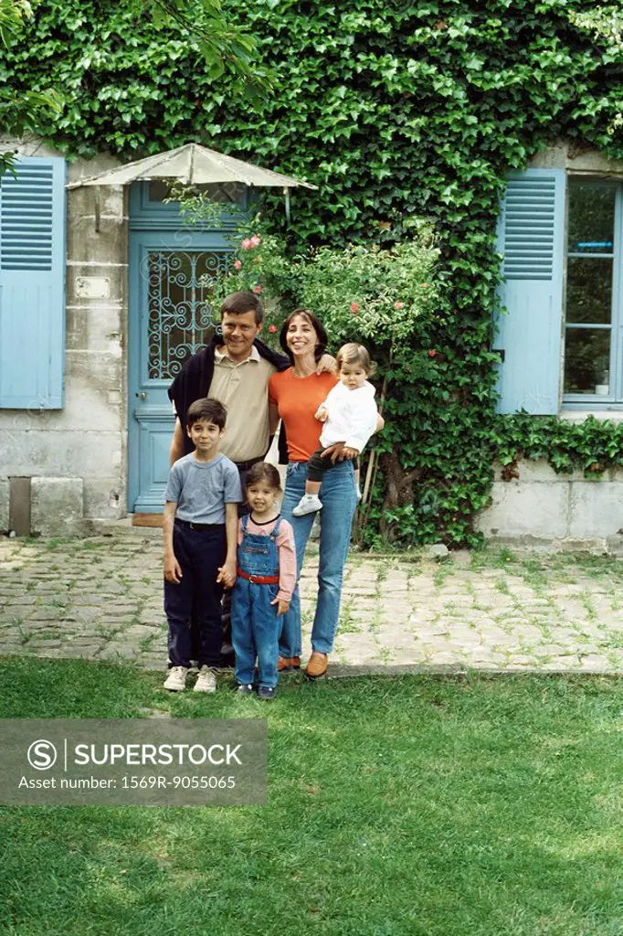 Family standing in front of house, portrait