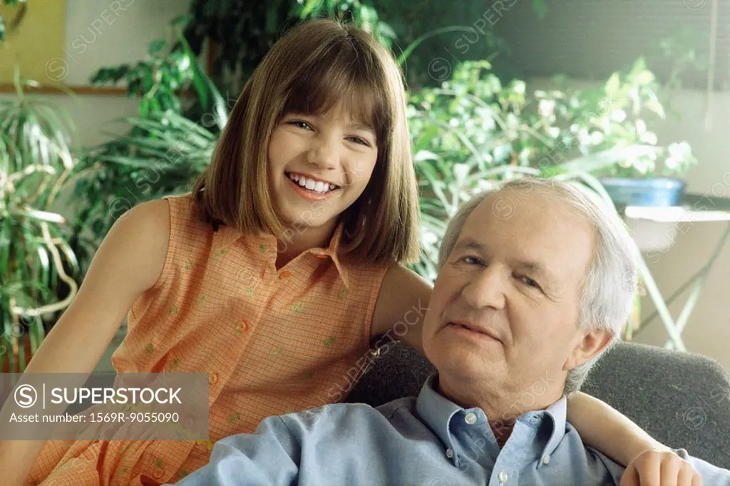 Grandfather and granddaughter smiling at camera, portrait