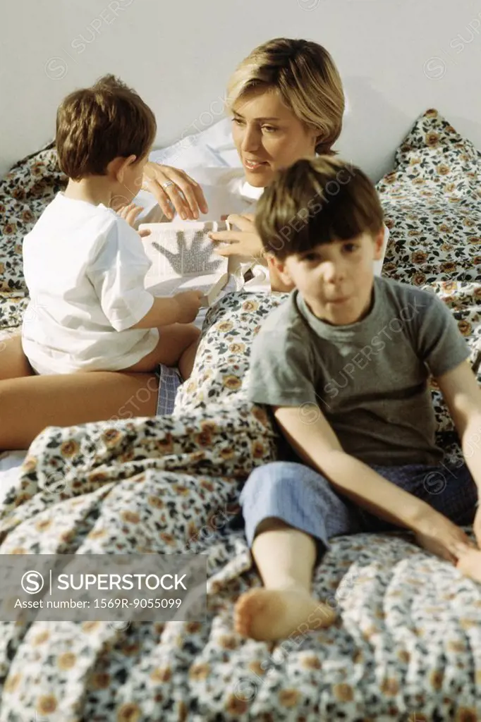 Mother and two children lazing around in bed