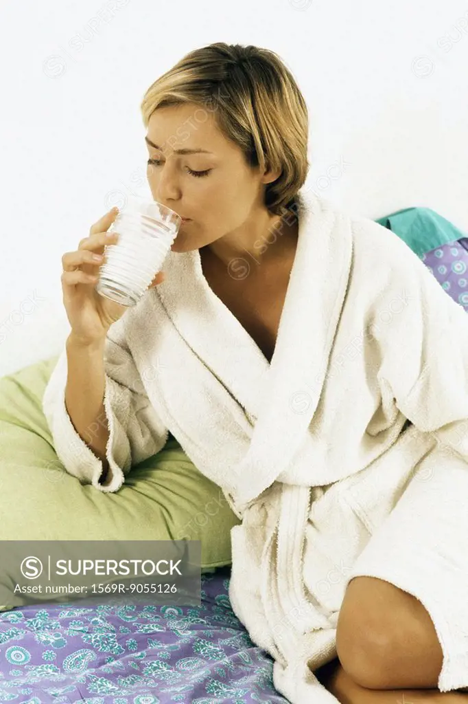 Woman in bathrobe drinking milk in bed