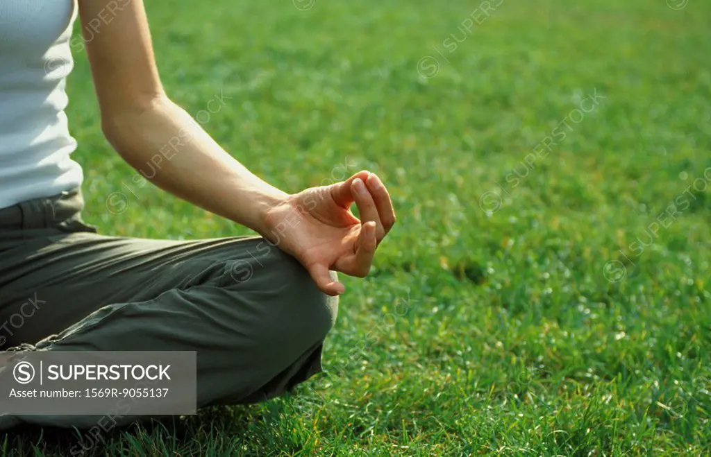 Woman sitting in lotus position on grass, cropped