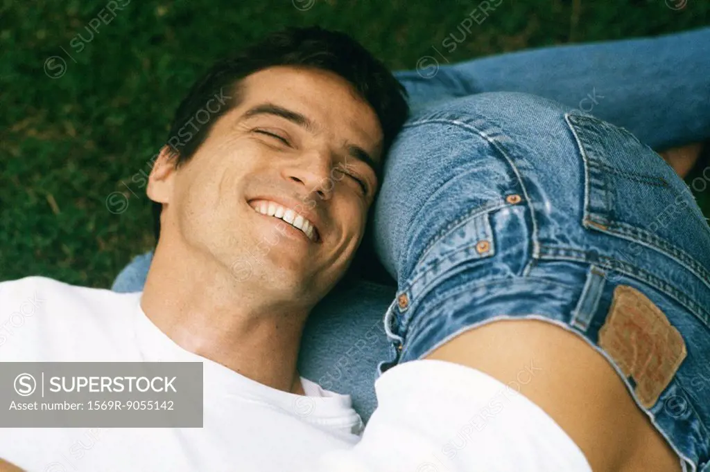 Man resting head on woman´s legs, laughing, cropped