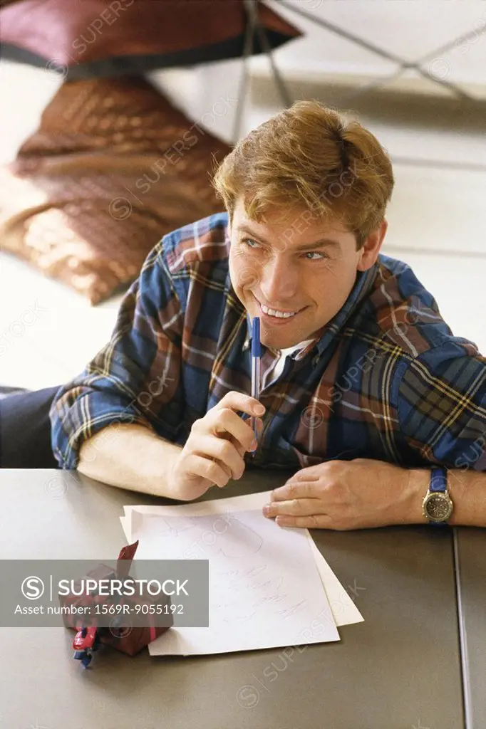 Man sitting at table writing letter, gift nearby