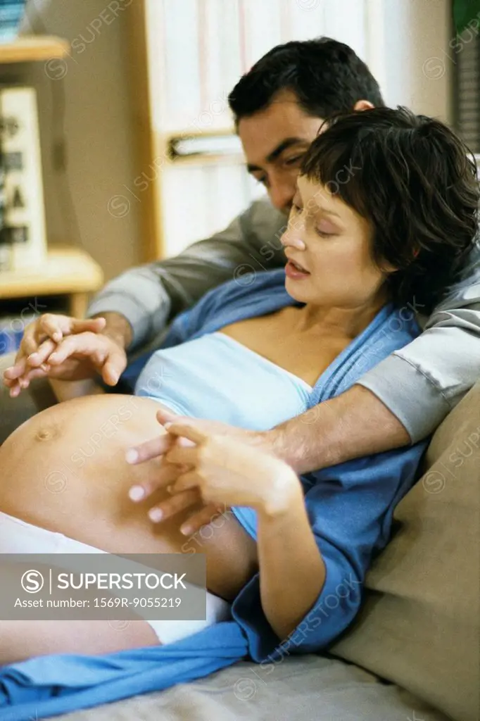 Couple with hands clasped over woman´s pregnant stomach