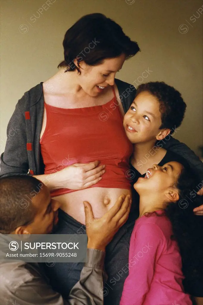 Husband and children gathered around pregnant woman, smiling