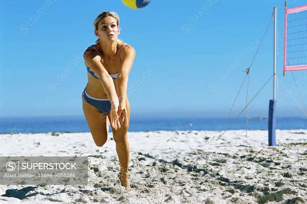 Female playing beach volleyball running to catch ball