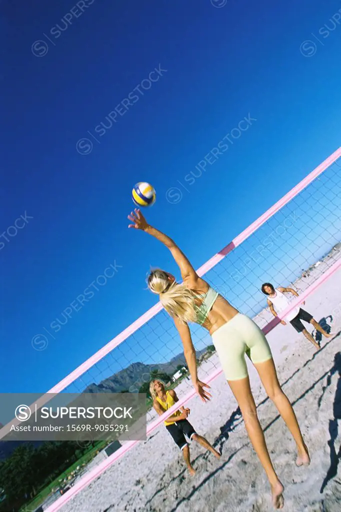 Female jumping to hit volleyball over net