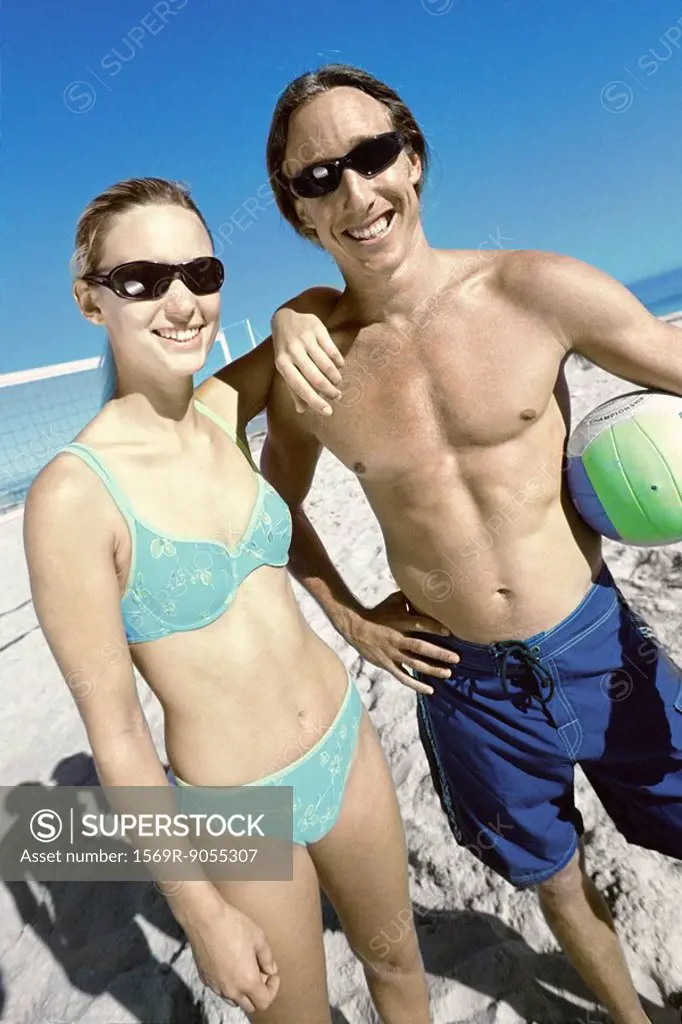 Young couple preparing to play beach volleyball
