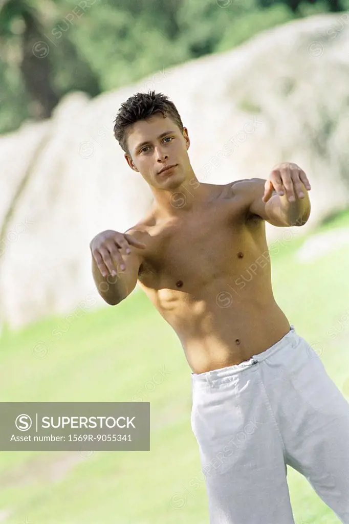 Male practicing tai chi chuan in park setting, front view