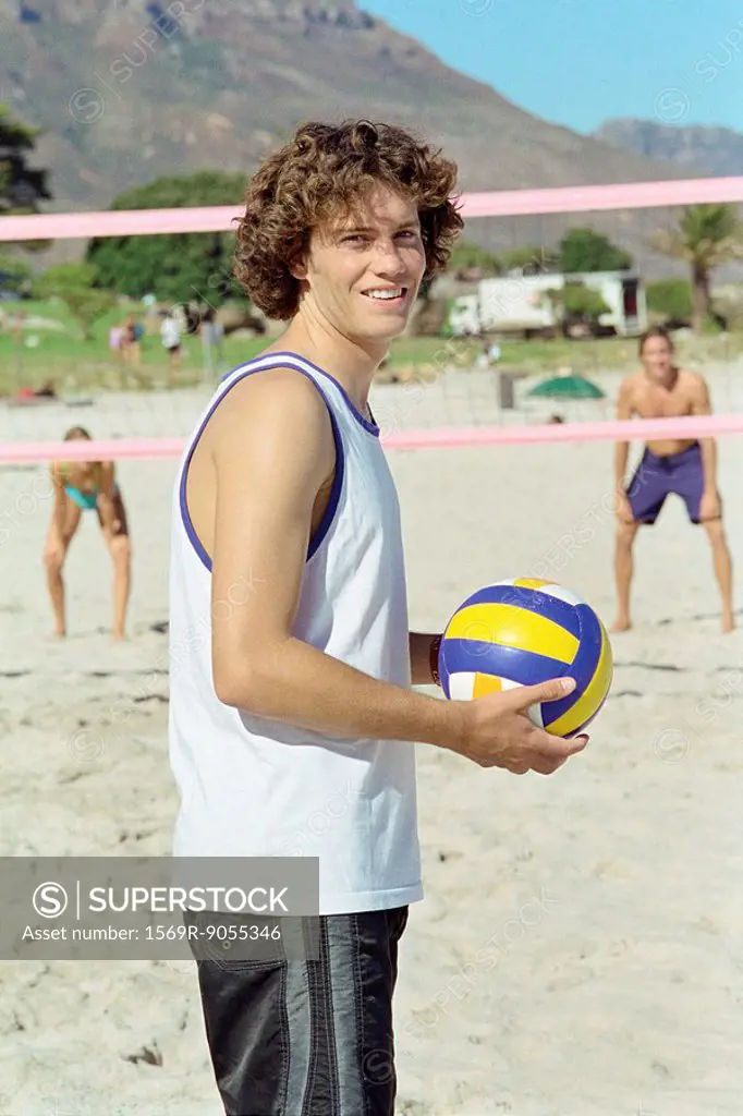 Male holding volleball, playing beach volleyball