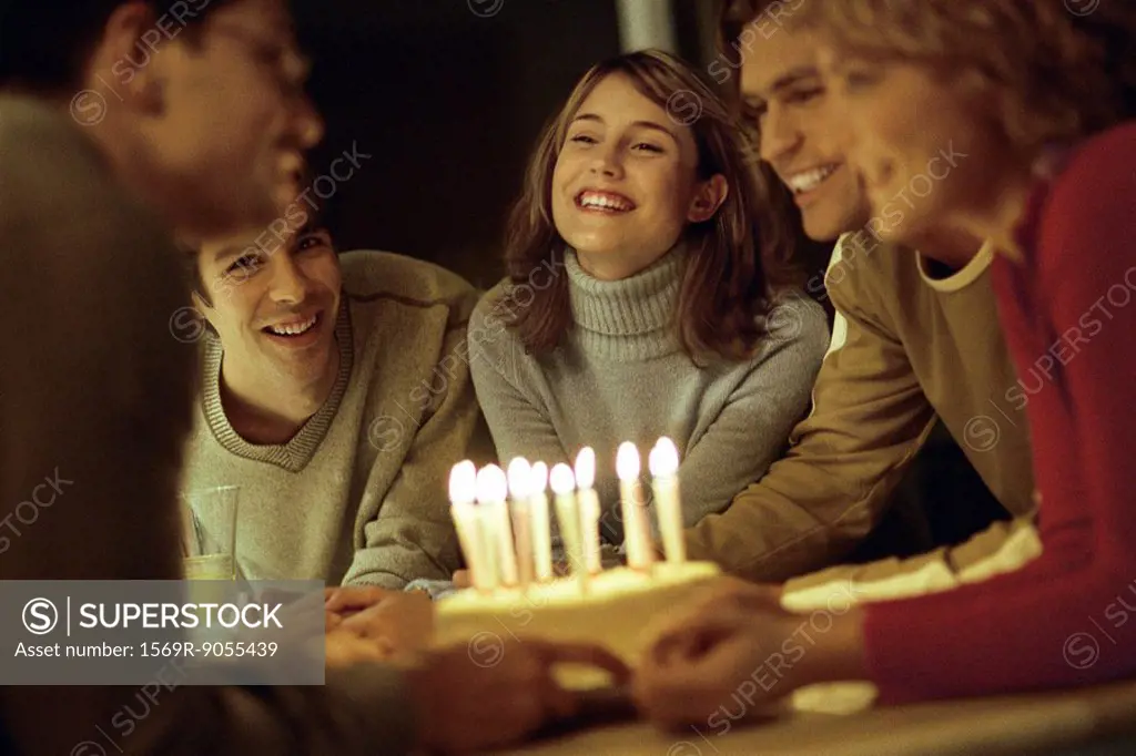 Friends gathered together presenting birthday cake to friend