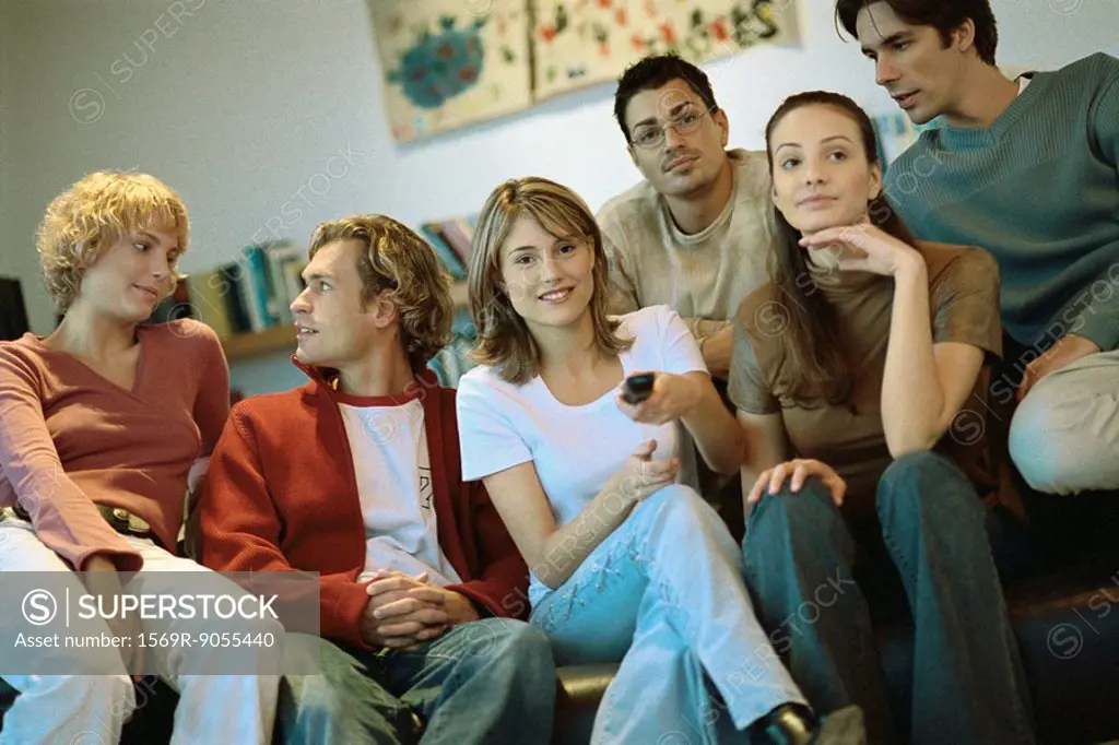 Group of friends sitting close together on sofa watching TV