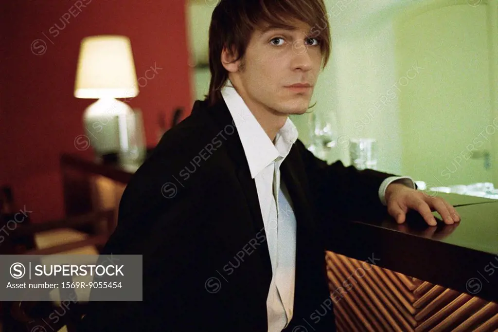 Well dressed young man at bar, looking at camera