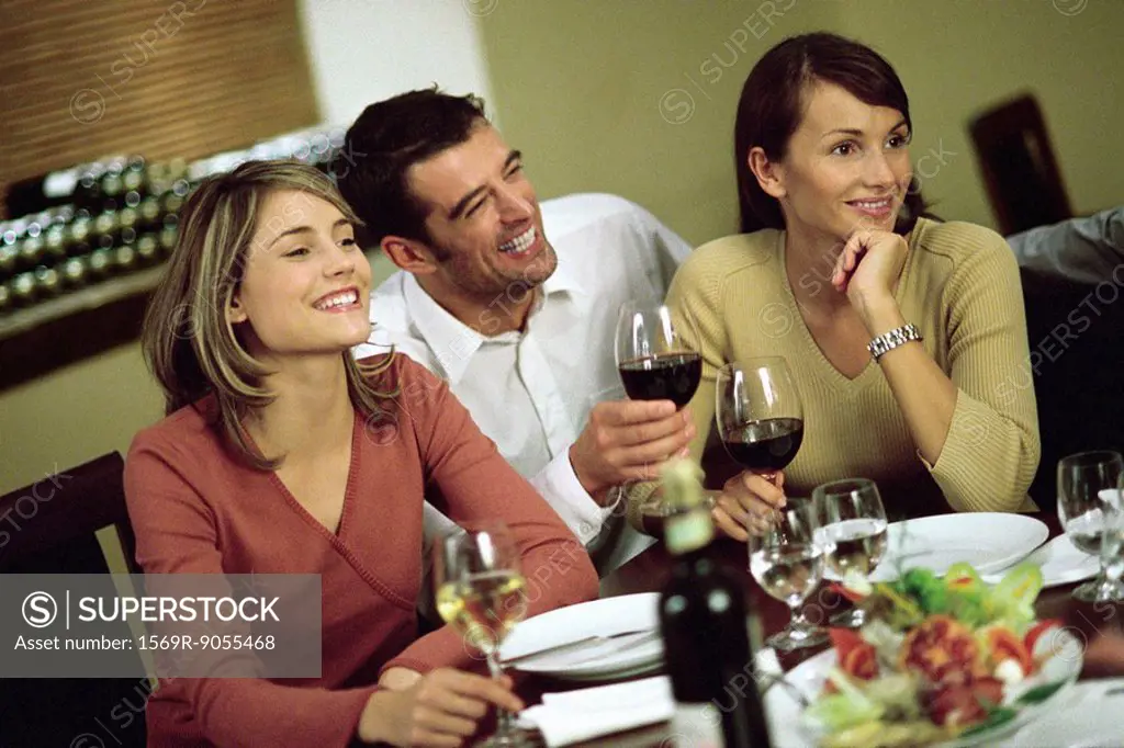 Man having wine with women at restaurant table