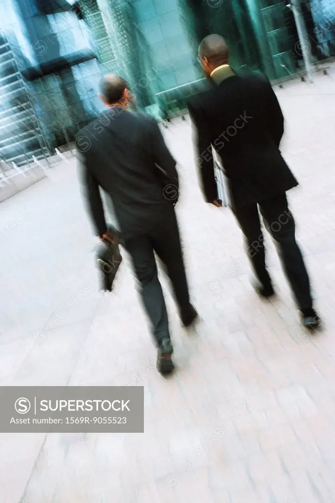 Businessmen walking together along city sidewalk