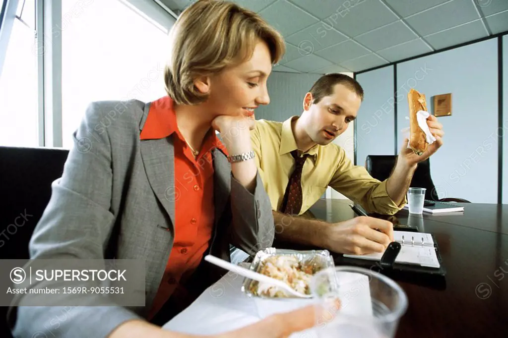 Business associates discussing calendar event over casual lunch in conference room