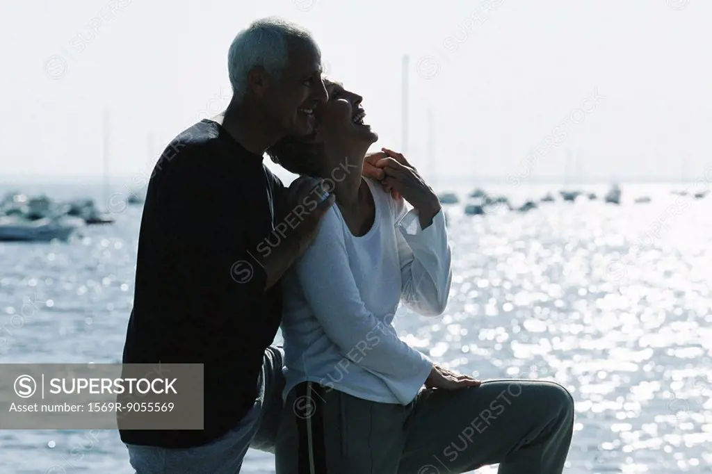 Mature couple laughing together, sea in background