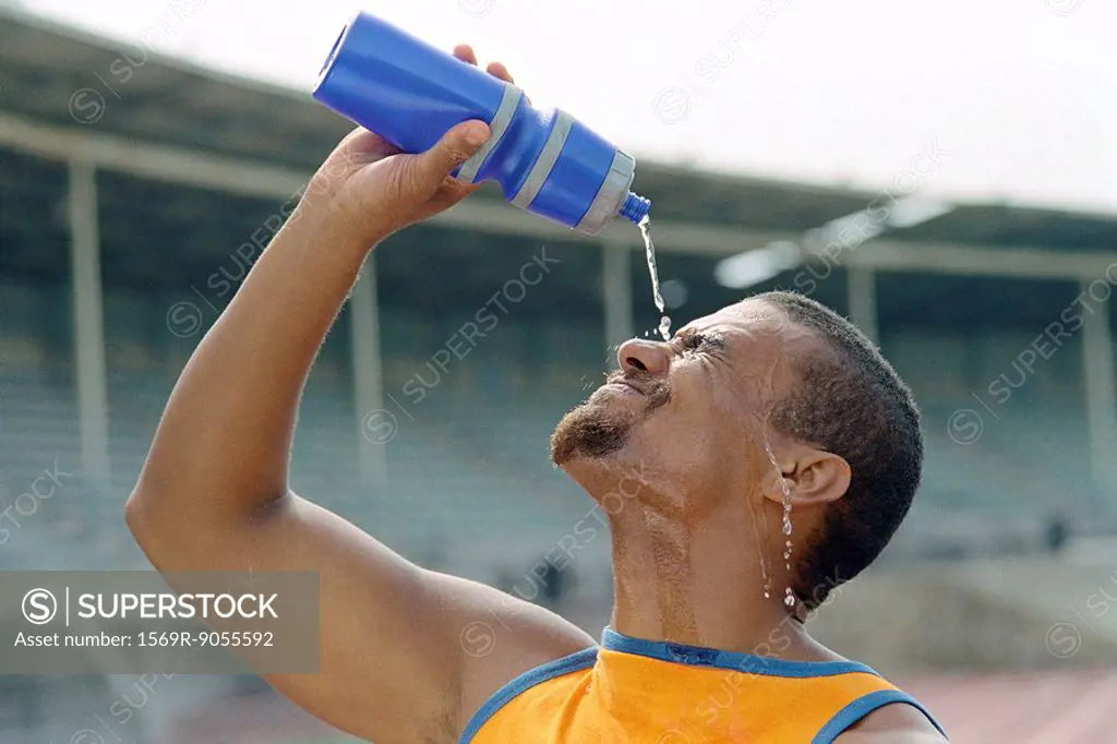 Athletic man pouring water on face