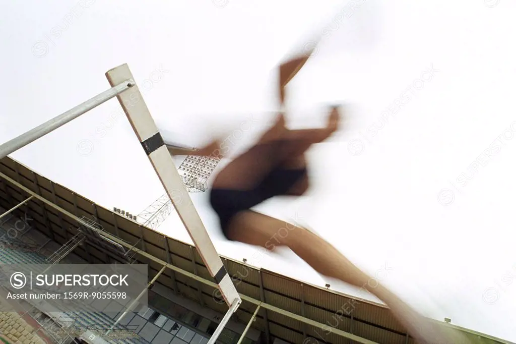 Runner jumping over hurdle, blurred