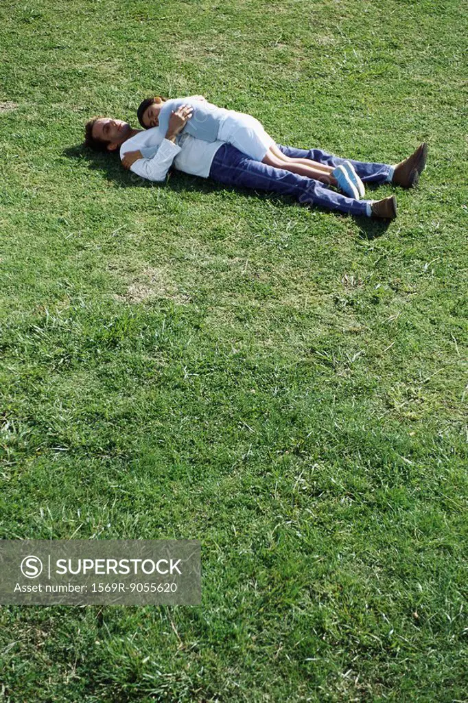 Father and daughter lying together in grassy field