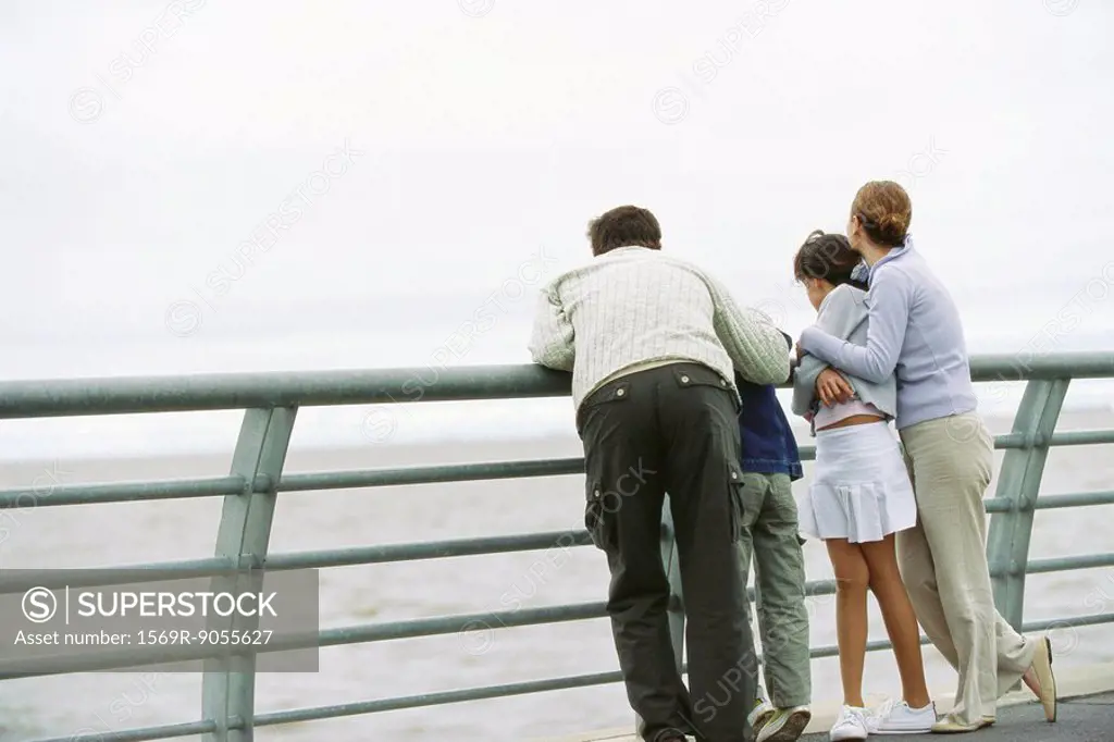 Family together at seawall railing looking at view