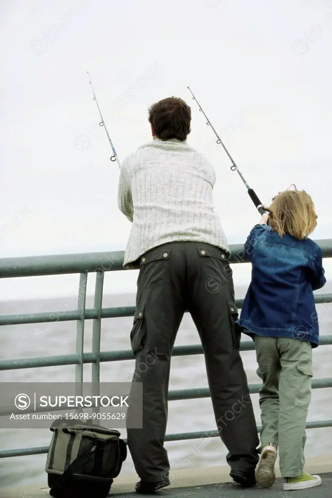 Father and son fishing from pier, rear view