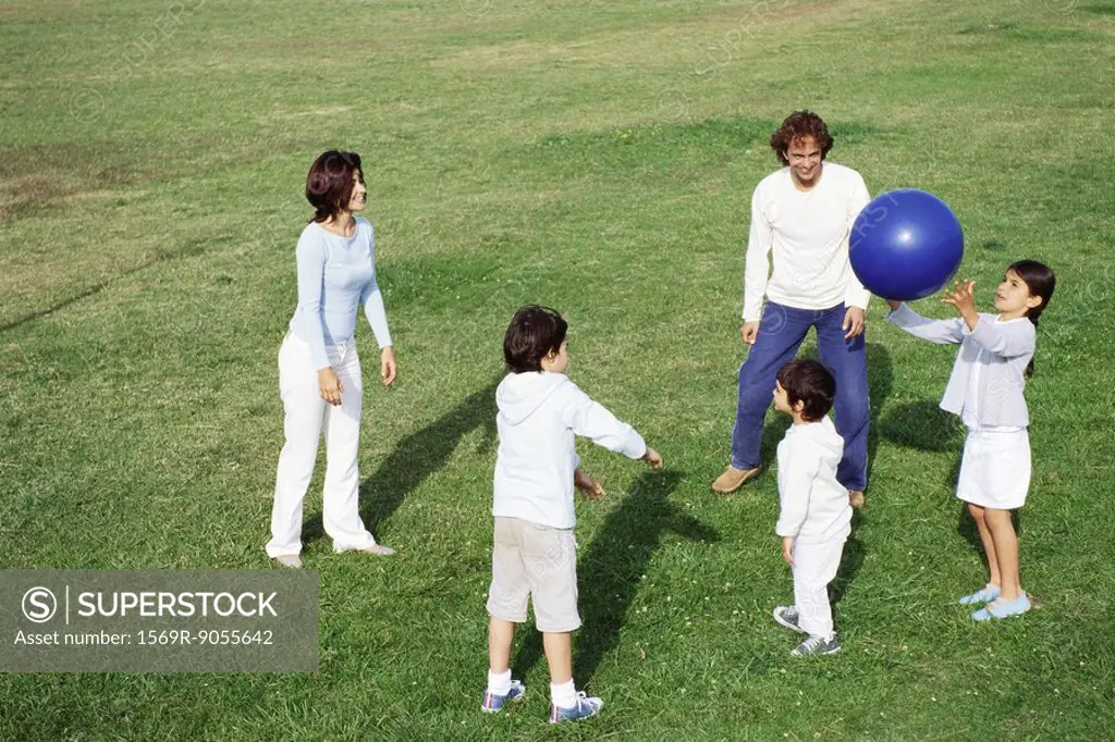 Family playing with ball in grassy field