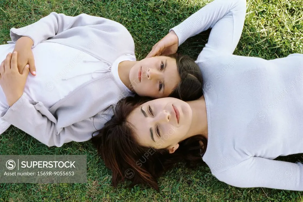 Mother and daughter reclining together in grass, viewed from directly above