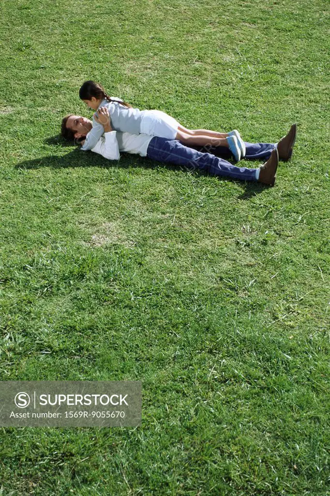 Father and daughter lying together in grassy field