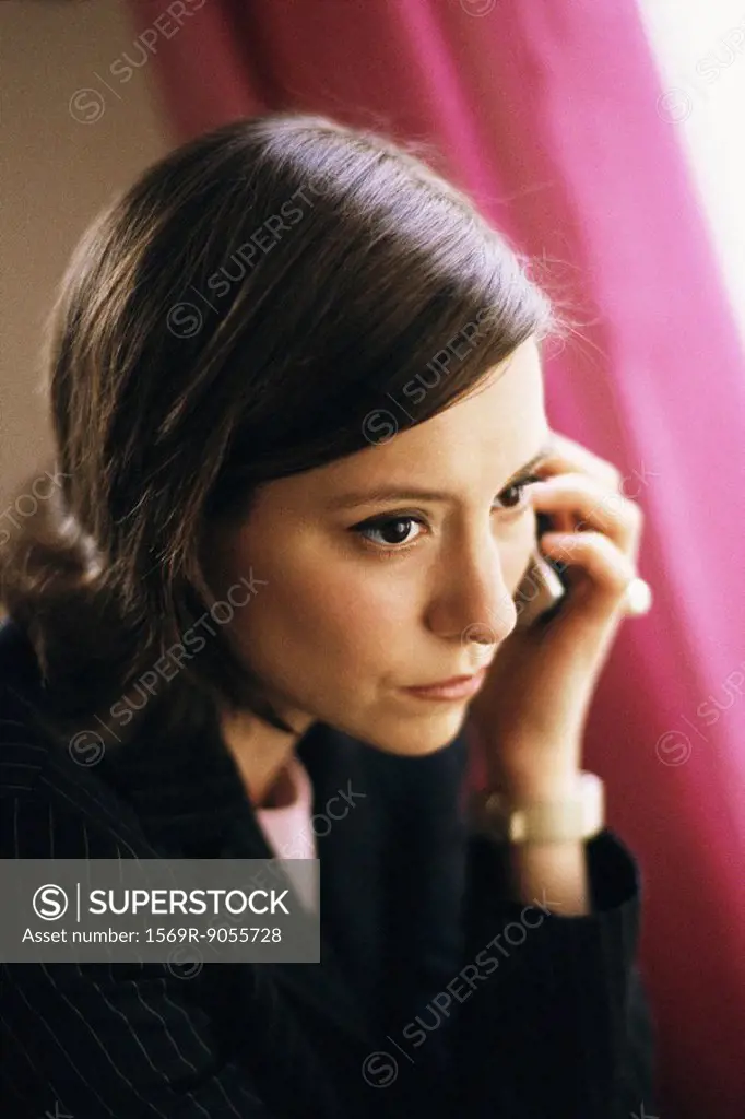 Woman listening to phone call, looking away pensively
