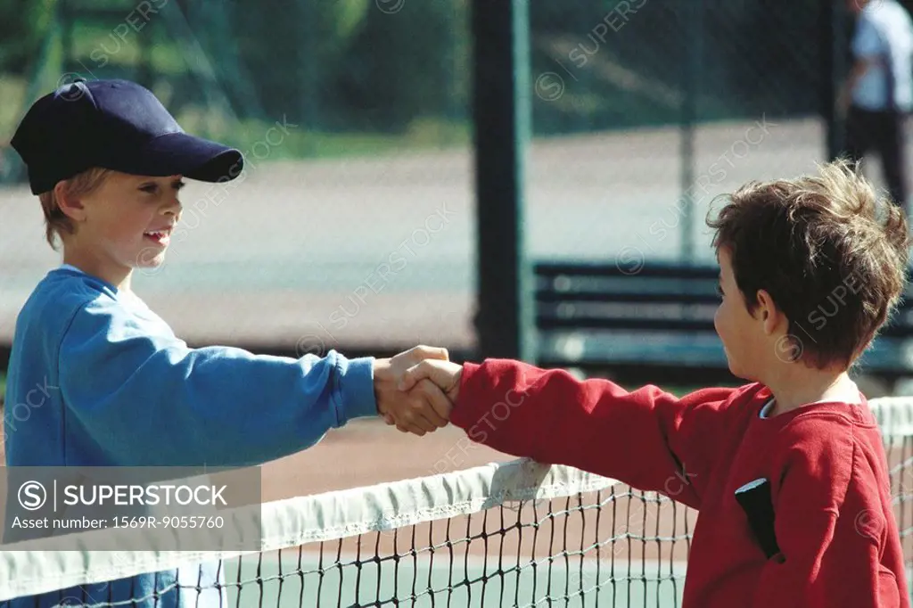 Girls shaking hands at net on tennis court