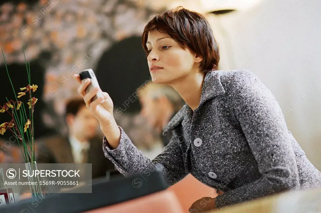 Woman sitting alone in restaurant, looking at cell phone