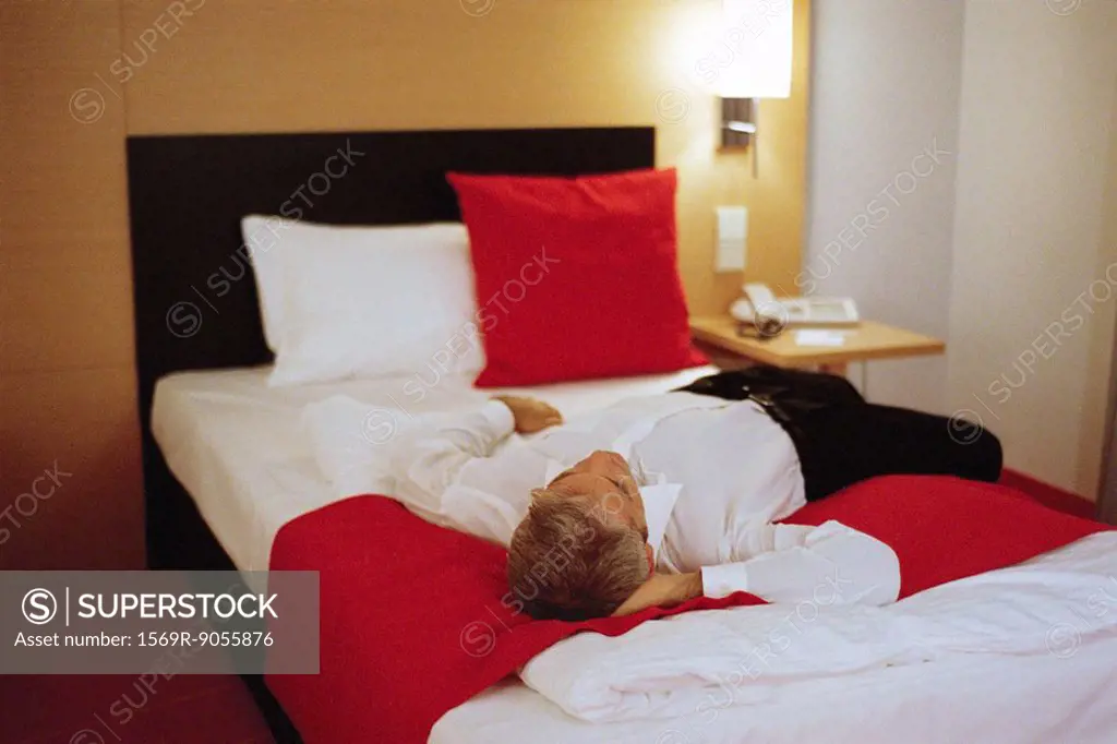 Businessman lying fully clothed on hotel bed