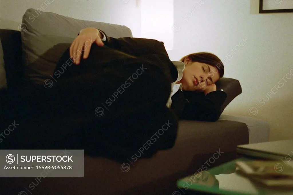 Businesswoman fully clothed sleeping on sofa