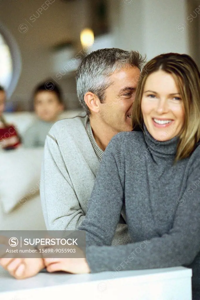 Couple sitting together, man whispering in woman´s ear