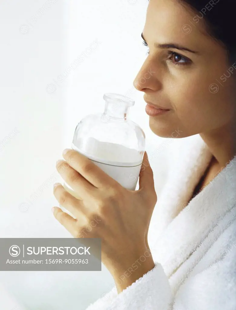 Woman smelling aroma from open bottle