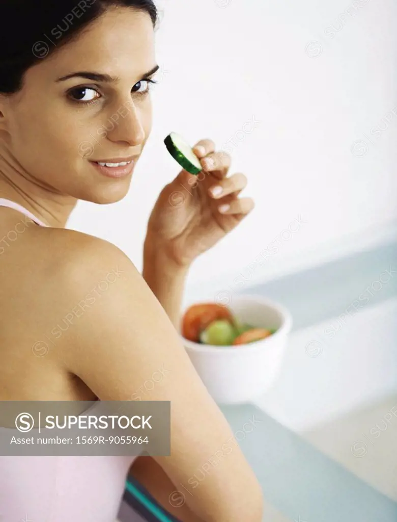 Young woman eating sliced raw vegetables